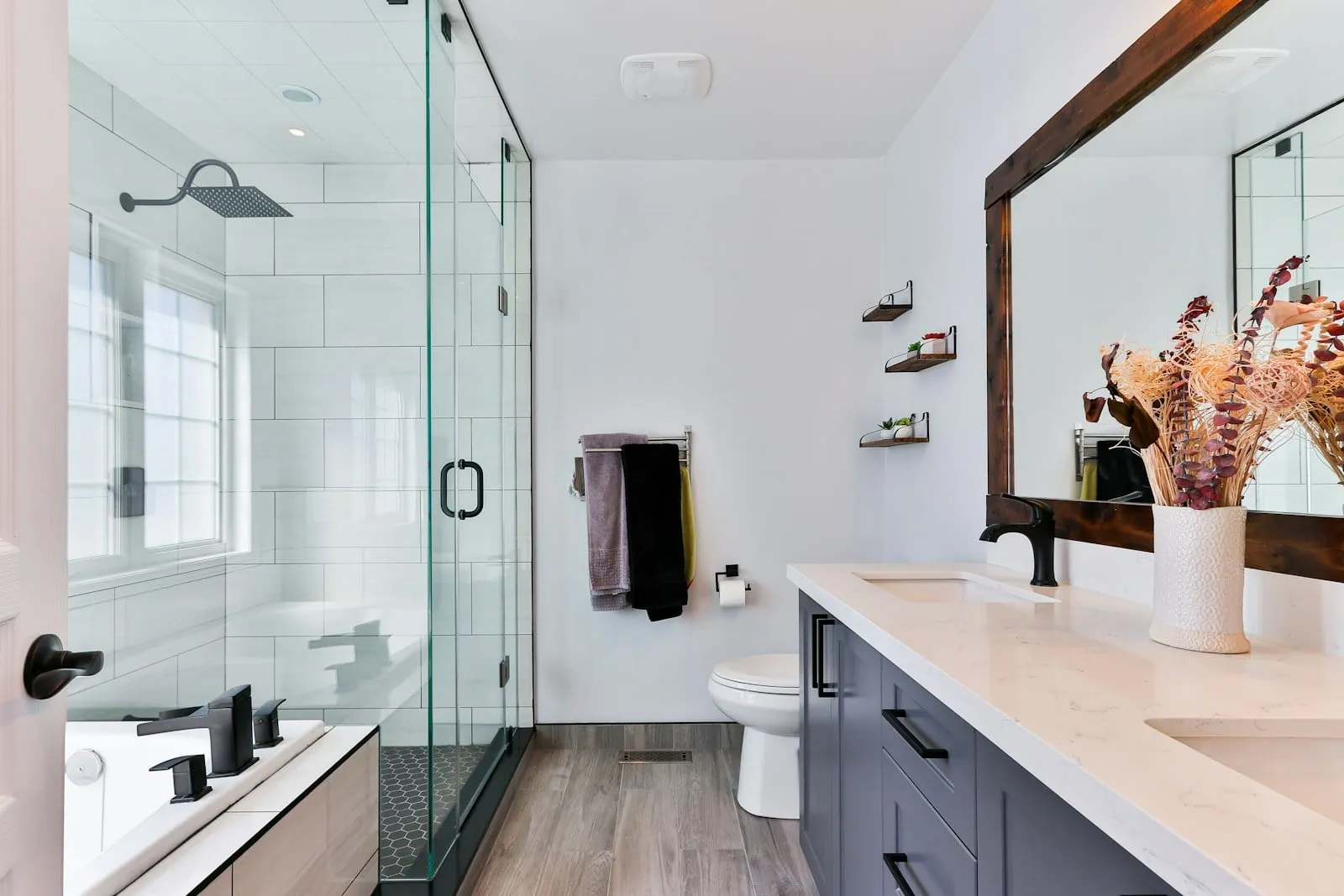 Une salle de bains claire et sa grande paroi de douche en verre